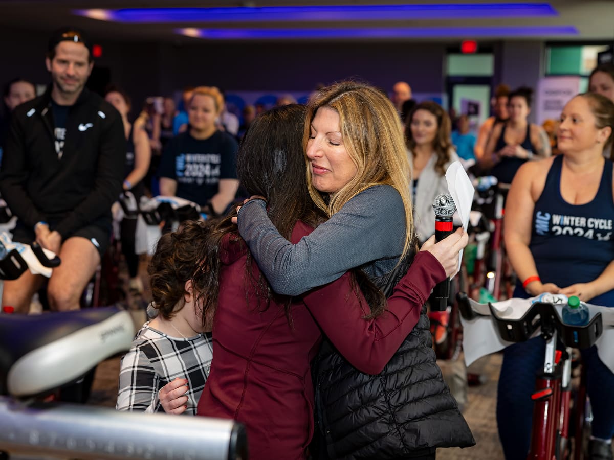 two people hugging at a PMC Winter Cycle event